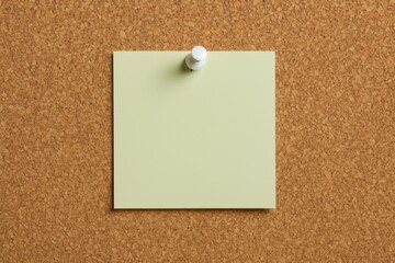 Green paper note pinned on cork board with a white pushpin
