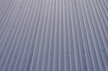 Sleek industrial blue gray corrugated metal roof texture with strong parallel lines and fasteners offering a modern abstract architectural background