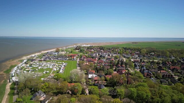 Dangast. Aerial view of coastal town with lush greenery, sandy beach, and calm waters, showcasing serene landscape and vibrant community life