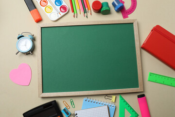 Top view of school supplies, pencils, erasers, paper clips and notebooks, on a beige background....