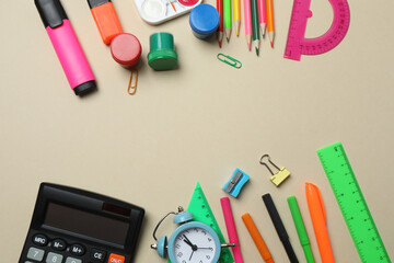Top view of school supplies, pencils, erasers, paper clips and notebooks, on a beige background....