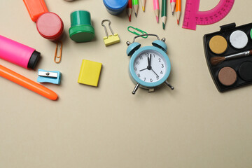 Top view of school supplies, pencils, erasers, paper clips and notebooks, on a beige background....