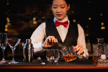 Professional female bartender preparing alcoholic drinks in a bar