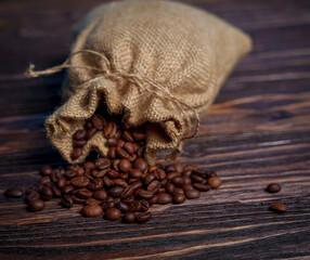 Coffee beans spilling from burlap sack onto dark wooden surface