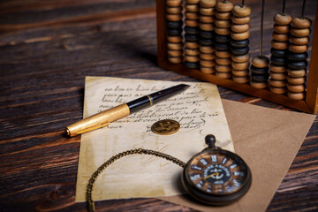 Vintage pocket watch with handwritten letter and pen on wooden surface