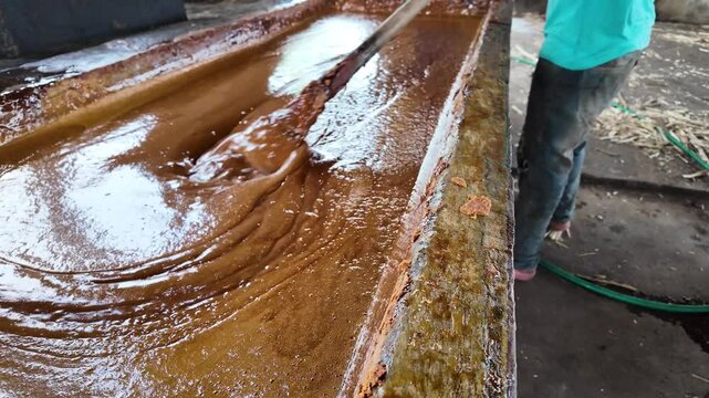Making panela in a traditional sugar mill, showing unrefined sugar flowing through the process