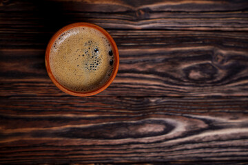 Cup of coffee on dark wooden table viewed from above