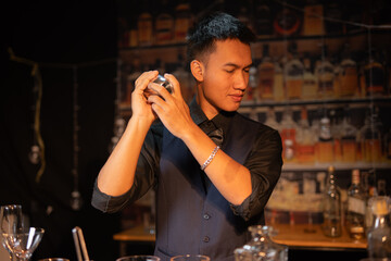 Professional male bartender preparing alcoholic drinks in a bar