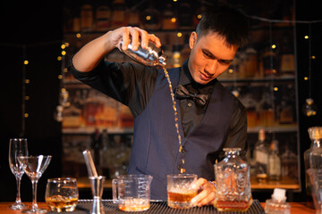 Professional male bartender preparing alcoholic drinks in a bar