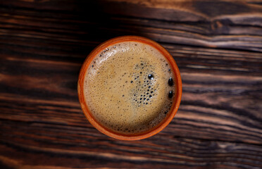 Cup of coffee on dark wooden table viewed from above