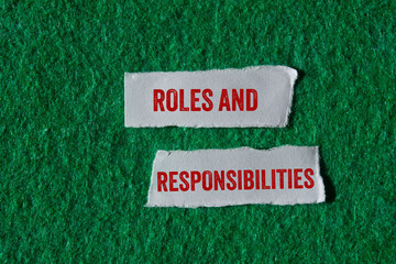 Roles and responsibilities message written on ripped torn paper pieces on green background. Conceptual roles and responsibilities symbol. Copy space.