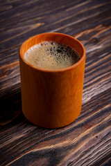 Cup of coffee on dark wooden table viewed from above
