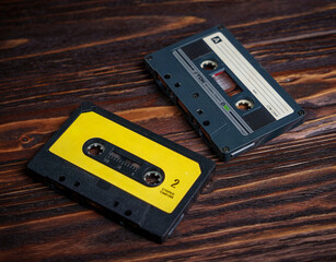 Two vintage audio cassette tapes on dark wooden surface