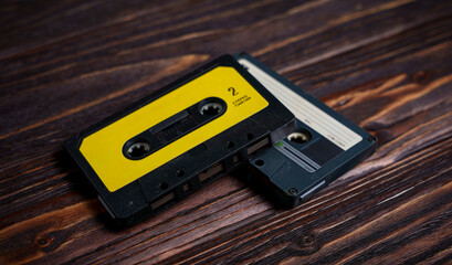 Two vintage audio cassette tapes on dark wooden surface