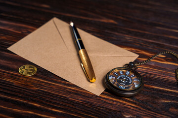 Vintage pocket watch, fountain pen, and envelope on wooden table
