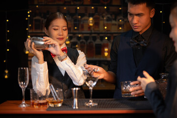 Professional female bartender preparing alcoholic drinks in a bar