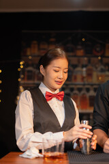 Professional female bartender preparing alcoholic drinks in a bar