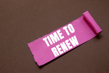 Time to renew message written on ripped torn pink paper piece on brown background. Conceptual time...