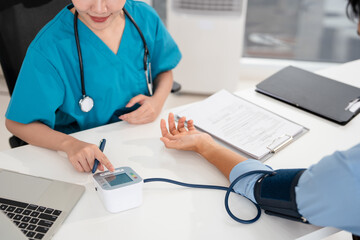Female doctor in scrub uniform measure blood pressure with electronic monitor in hospital. Caring...