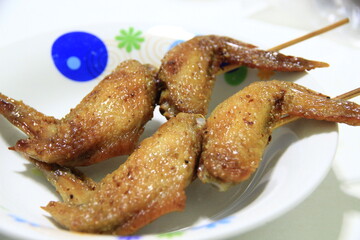 2 skewers of grilled chicken wings ready to eat in a bowl.