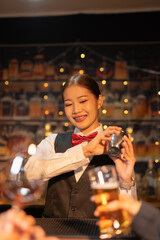 Professional female bartender preparing alcoholic drinks in a bar