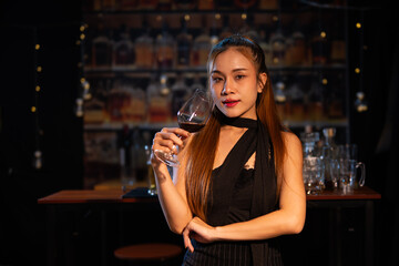 Beautiful young woman drinking alcohol at nightclub bar enjoying a pub party