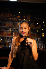 Beautiful young woman drinking alcohol at nightclub bar enjoying a pub party