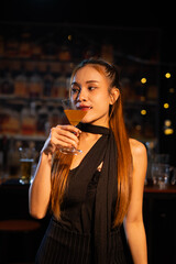 Beautiful young woman drinking alcohol at nightclub bar enjoying a pub party