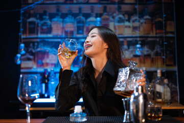 Beautiful young woman drinking alcohol at nightclub bar enjoying a pub party
