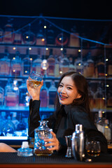 Beautiful young woman drinking alcohol at nightclub bar enjoying a pub party