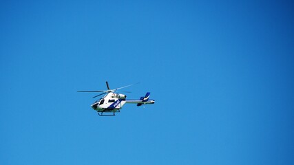police helicopter patrols flying in blue cloudless sky