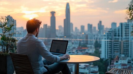 A travel blogger sitting on a hotel rooftop deck working on a laptop while enjoying the city skyline view