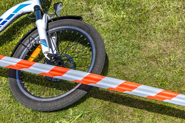 The scene of a bicycle accident surrounded by red and white warning tape, a cyclist's accident,