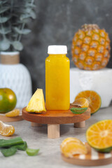 Tropical Pineapple Orange Aloe Vera Juice Bottle with Fresh Fruit on Wooden Tray