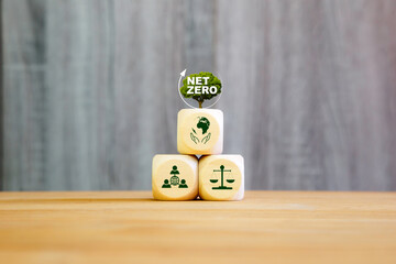 Wooden blocks with icons for environment, society, and governance, topped with a Net Zero tree symbol. Concept of ESG strategy and sustainable carbon neutrality.