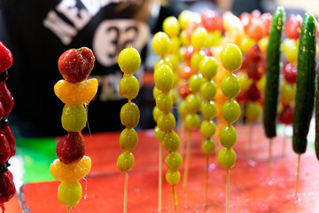 A close-up of glossy, red candied hawthorn sticks (Tanghulu) on display at a traditional night...