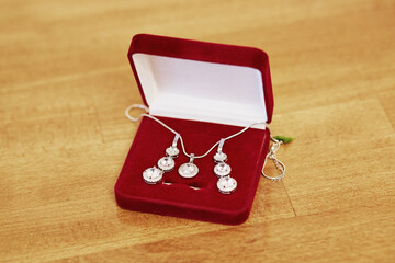A set of three necklaces and earrings are displayed in a red velvet box
