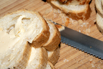 Sliced and buttered French stick baguette bread ready for dinner food prep with knife