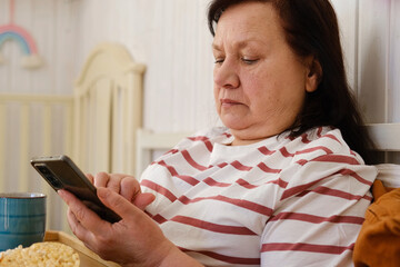 Senior woman having breakfast sitting in bed, drinking tea, enjoying her morning at home. Old lady...