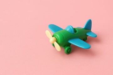 Miniature plastic airplane with blank space on a pink backdrop, designed as a toy.