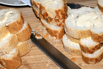 Sliced and buttered French stick baguette bread ready for dinner food prep with knife