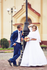 A bride and groom are posing for a picture in front of a church