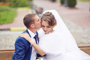A bride and groom are sitting on a bench