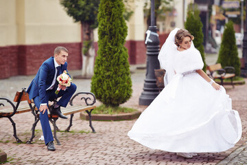 A bride and groom are standing in front of a bench