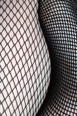 Close up of black fishnet tights on skin legs curves abstract background