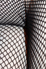 Close up of black fishnet tights on skin legs curves abstract background