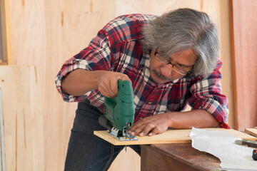 Elderly lifestyle concept, senior carpenter working in own small business carpentry shop, healthy...