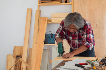 Elderly lifestyle concept, senior carpenter working in own small business carpentry shop, healthy...