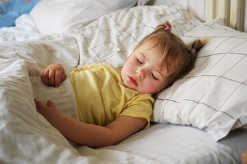 Peaceful adorable baby sleeping on a bed at home. Slumbering little child. Two years old girl sleeps peaceful at domestic room interior background. Serene dream. Cute face close up. Deep kid slumber