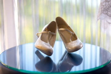 White shoes elegantly displayed. A pair of delicate white shoes is showcased on a glass surface...